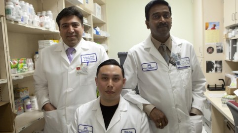 Three male pharmacy workers posing in their white lab coats 