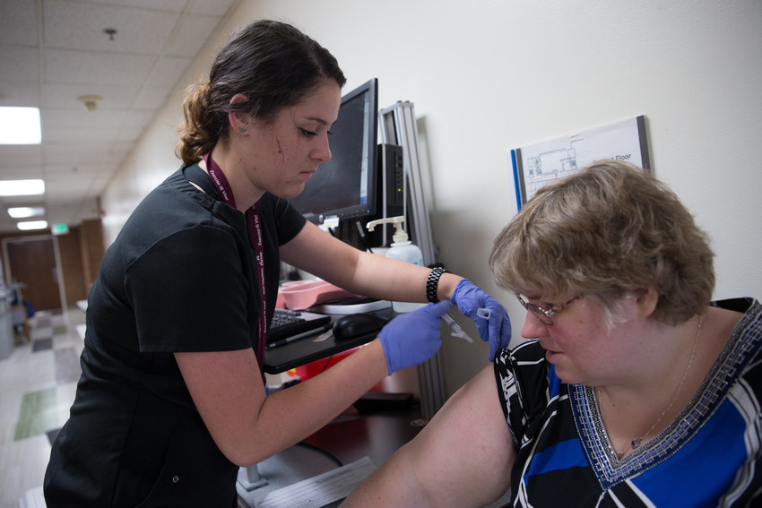 Nurse giving a female patient a flu shot 