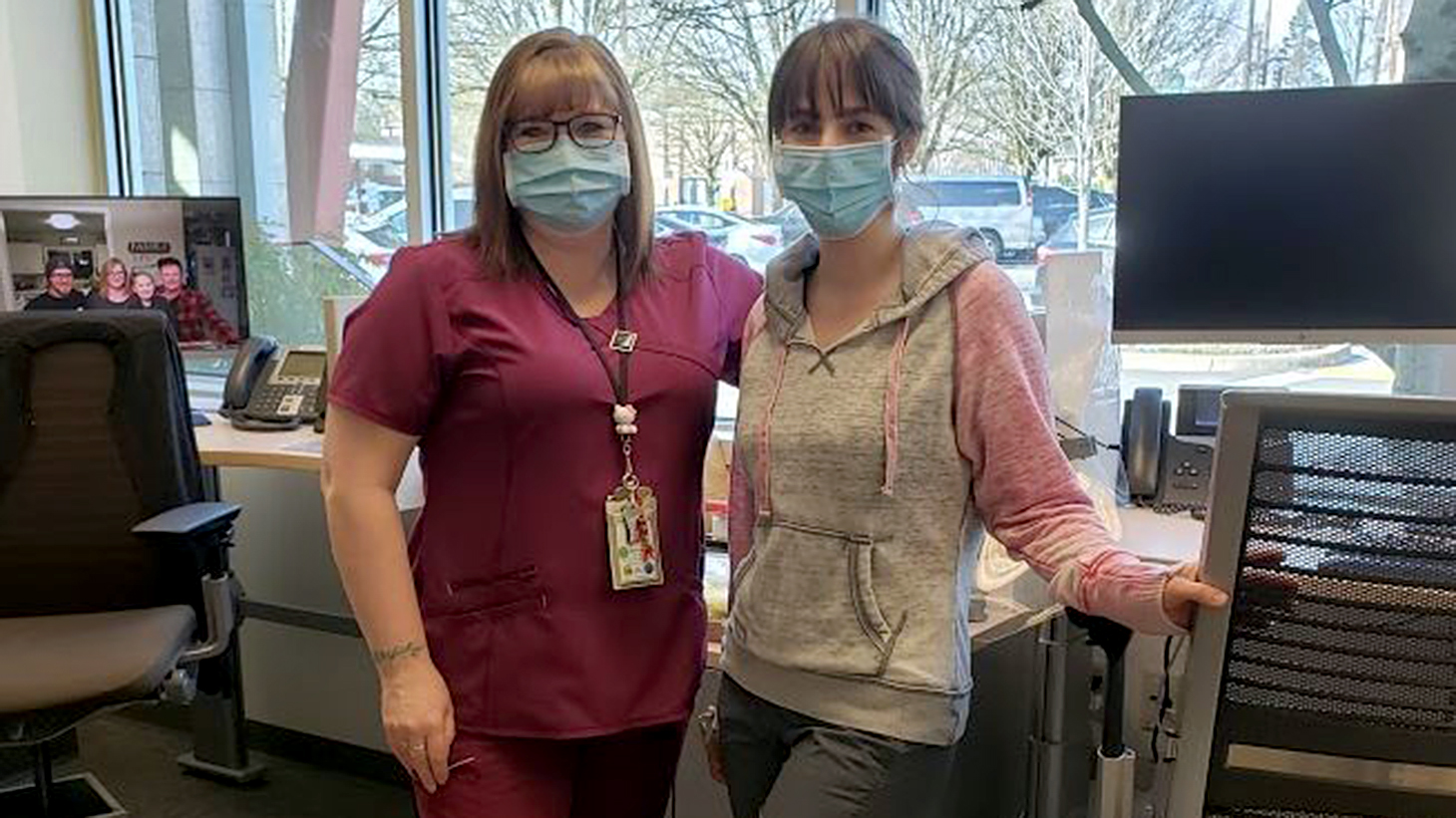 Two women posing together in an office