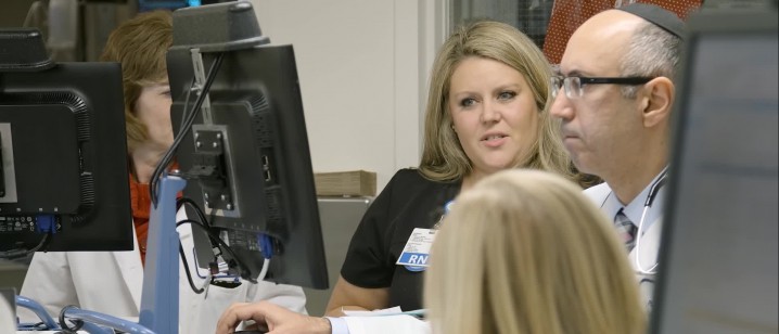 Doctors and nurses huddle around a computer