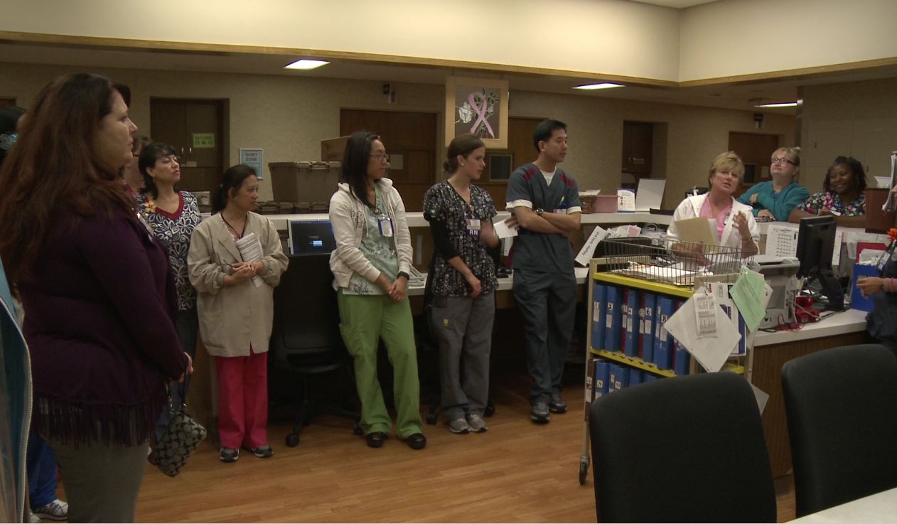 Members of a health care team huddle at the nurses' station 